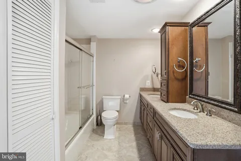 a bathroom with a granite countertop sink toilet mirror and shower