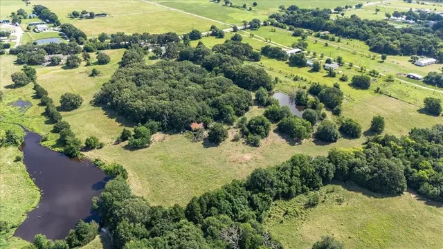 an aerial view of residential houses with outdoor space and trees all around