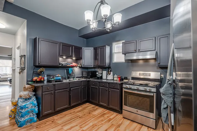 a kitchen with stainless steel appliances granite countertop a stove top oven a sink dishwasher and cabinets with wooden floor