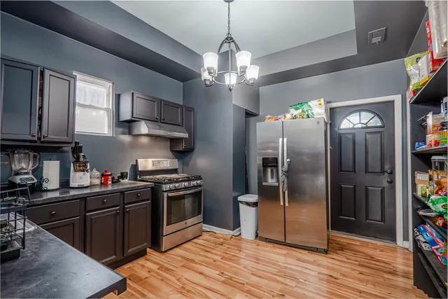 a kitchen with stainless steel appliances granite countertop a stove a refrigerator and a sink with wooden floor