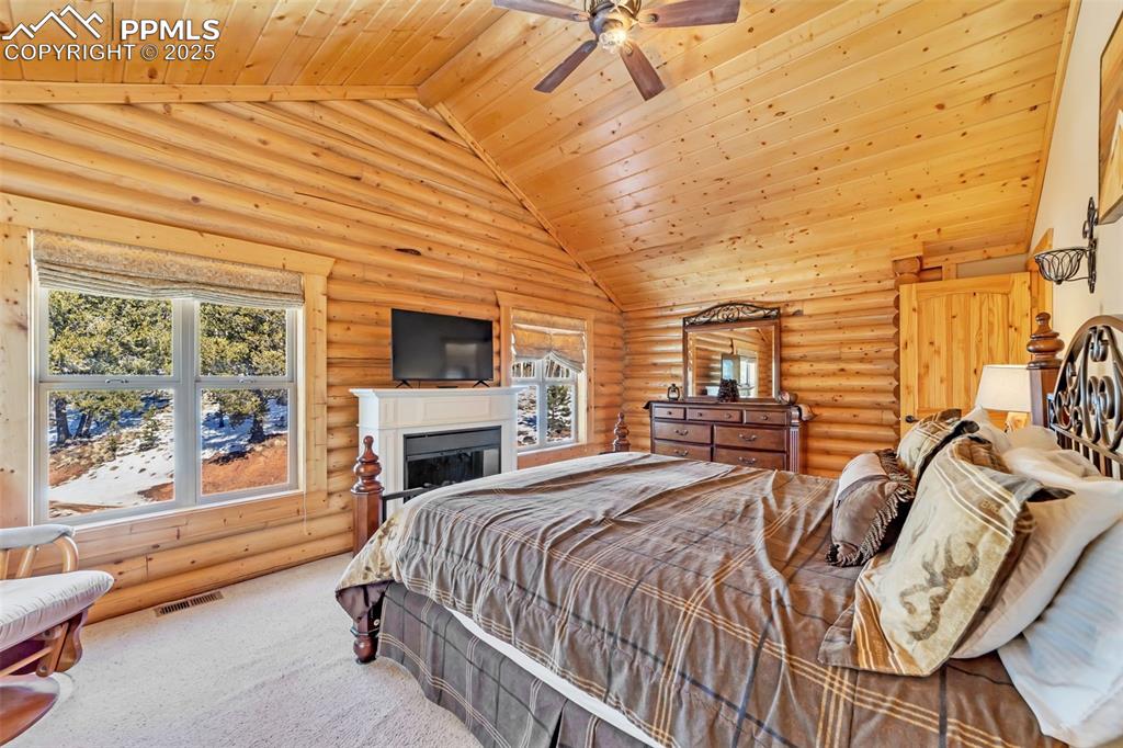 17549 Highway 67 Divide, CO 80814 - Photo 20 of 46 a bedroom with a bed a fireplace and dresser next to a window