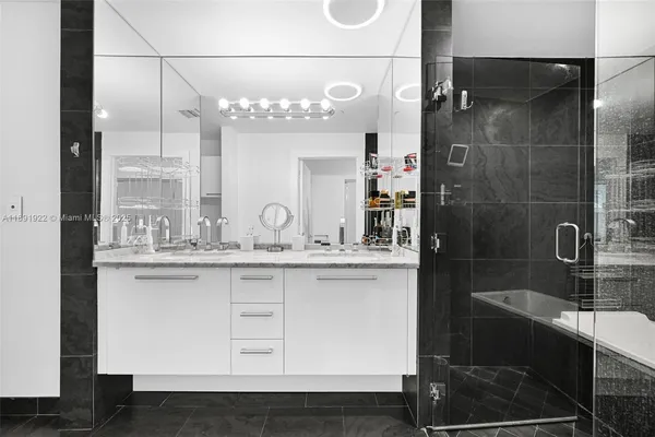a bathroom with a granite countertop sink a mirror and shower