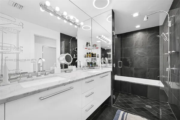 a bathroom with a sink a large mirror and shower
