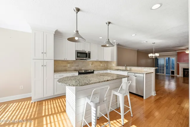 a kitchen with kitchen island granite countertop a sink a center island and stainless steel appliances