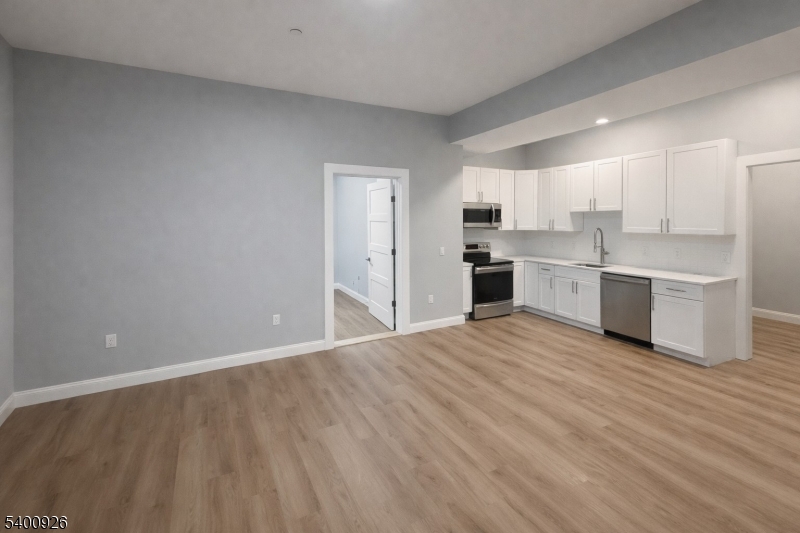 a large kitchen with stainless steel appliances a large counter top a stove a sink dishwasher and a refrigerator