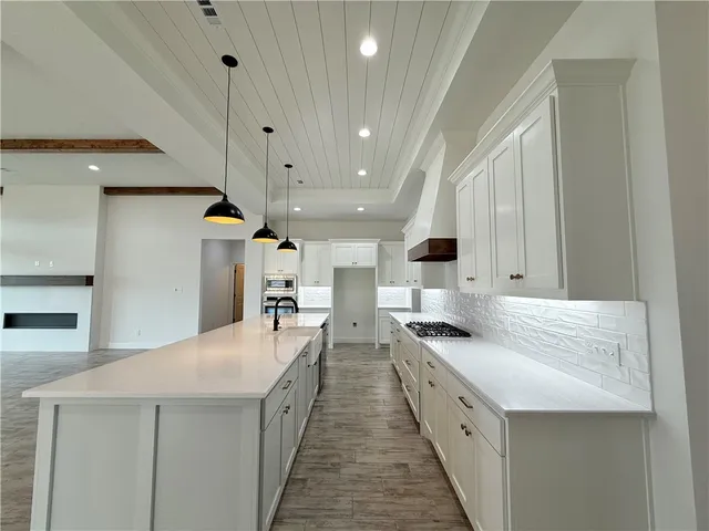 a kitchen with stainless steel appliances granite countertop a sink a stove a refrigerator and island with wooden floor