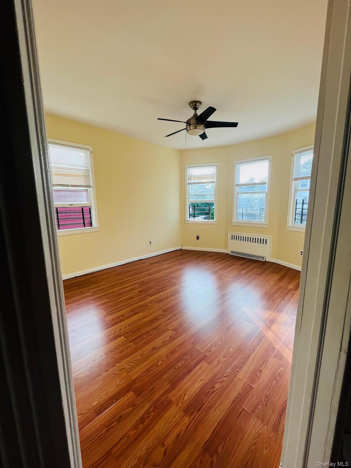 an empty room with wooden floor and windows
