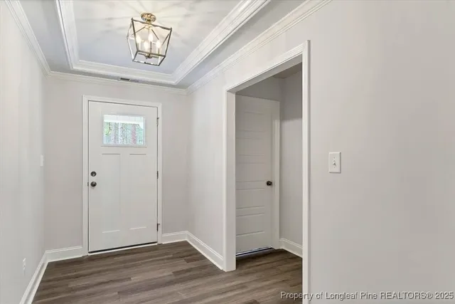 an empty room with wooden floor chandelier and windows