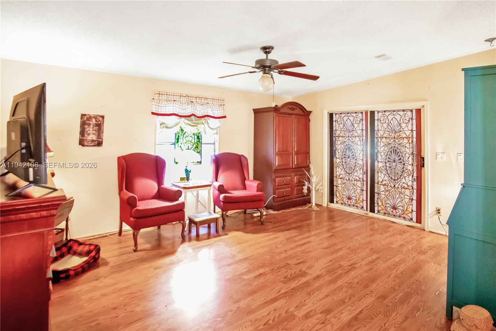 35250 Southwest 177th Court, Unit 48 Homestead, FL 33034 - Photo 7 of 29 a living room with furniture a flat screen tv and a floor to ceiling window