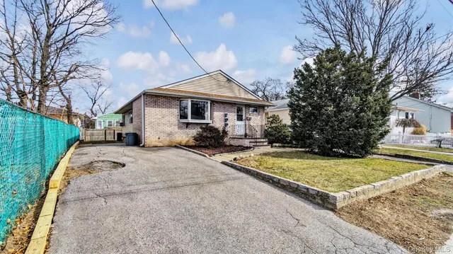 a view of a white house with a small yard and large tree