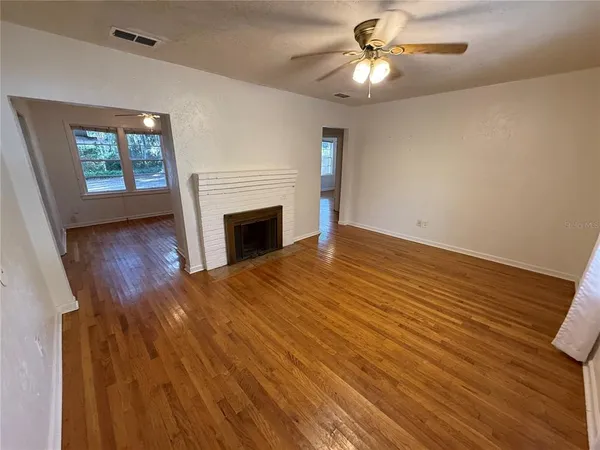 a view of empty room with wooden floor and fan