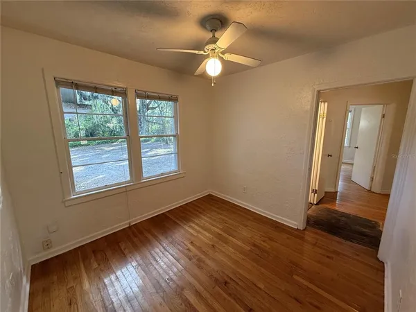a view of an empty room with wooden floor and a window