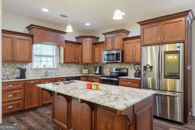 a kitchen with stainless steel appliances granite countertop a refrigerator a sink a stove a microwave and wooden cabinets