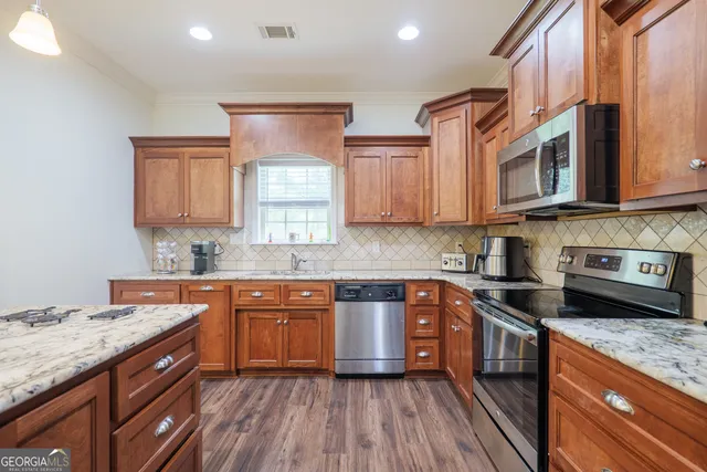 a kitchen with stainless steel appliances granite countertop wooden cabinets and a stove top oven