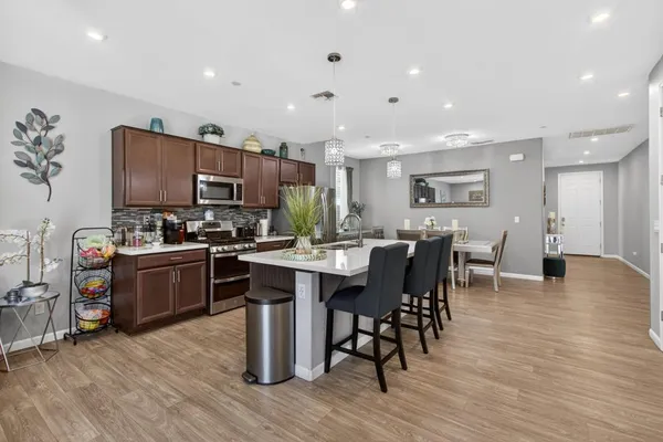 a kitchen with stainless steel appliances a dining table chairs and stove top oven