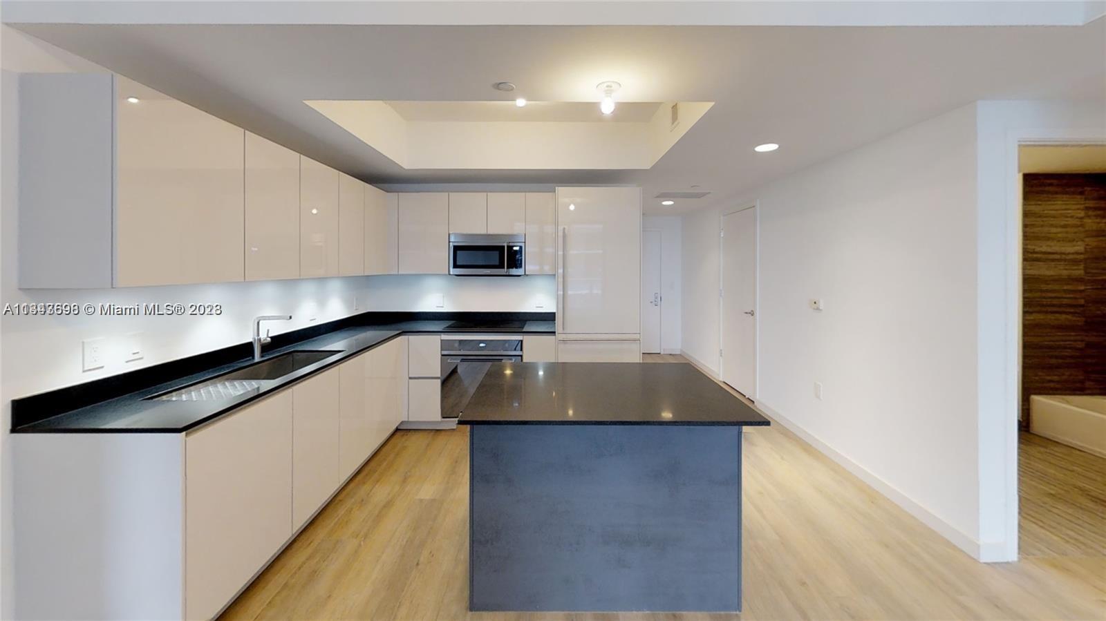 1010 Brickell Avenue, Unit 3209 Miami, FL 33131 - Photo 1 of 17 a kitchen with kitchen island granite countertop a sink a stove and cabinets