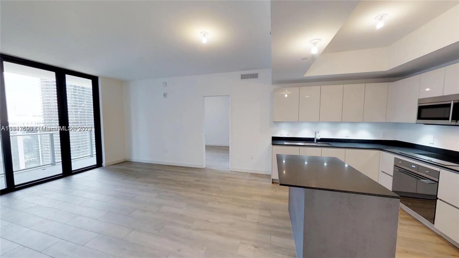 1010 Brickell Avenue, Unit 3209 Miami, FL 33131 - Photo 3 of 17 a kitchen with granite countertop a stove a sink and a refrigerator
