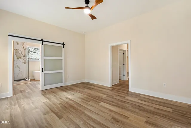 a view of an empty room with a window and wooden floor