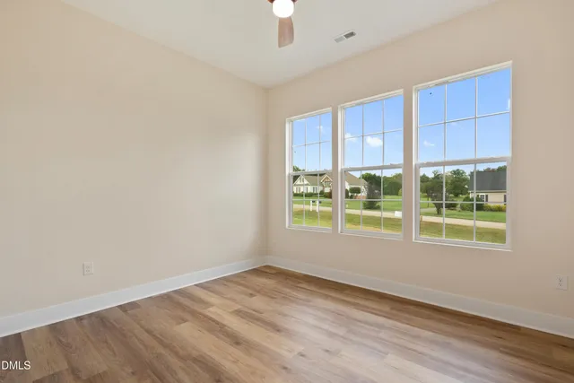 an empty room with wooden floor cabinet and windows