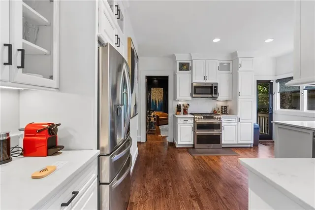 a kitchen with stainless steel appliances granite countertop a stove a refrigerator a sink a dining table and chairs with wooden floor