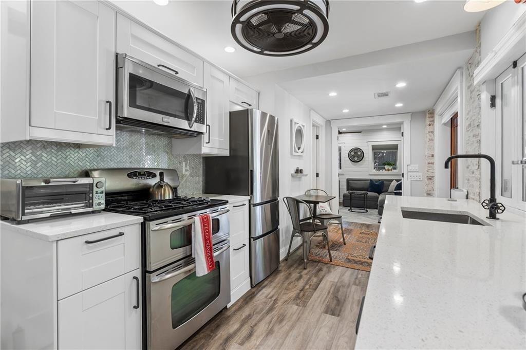 663 Yorkshire Road Northeast Atlanta, GA 30306 - Photo 68 of 85 a kitchen with stainless steel appliances granite countertop a stove top oven a sink dishwasher and white cabinets with wooden floor