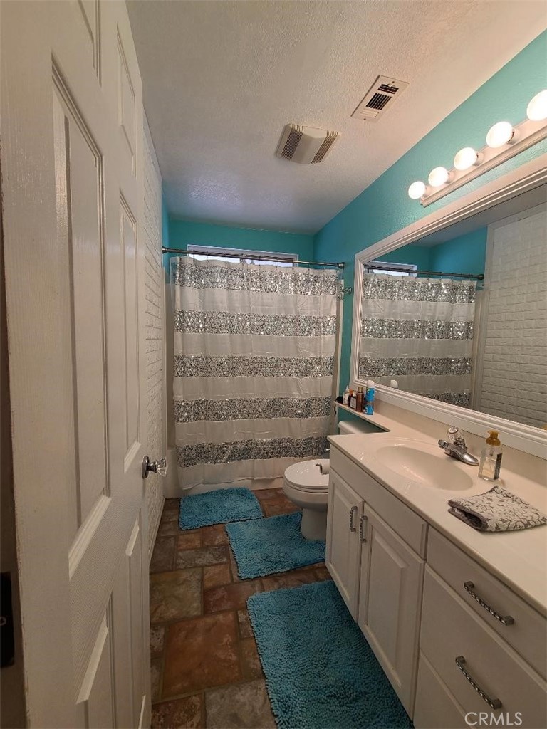 8725 Monte Vista Road Phelan, CA 92371 - Photo 13 of 31 a bathroom with a granite countertop sink a toilet and shower