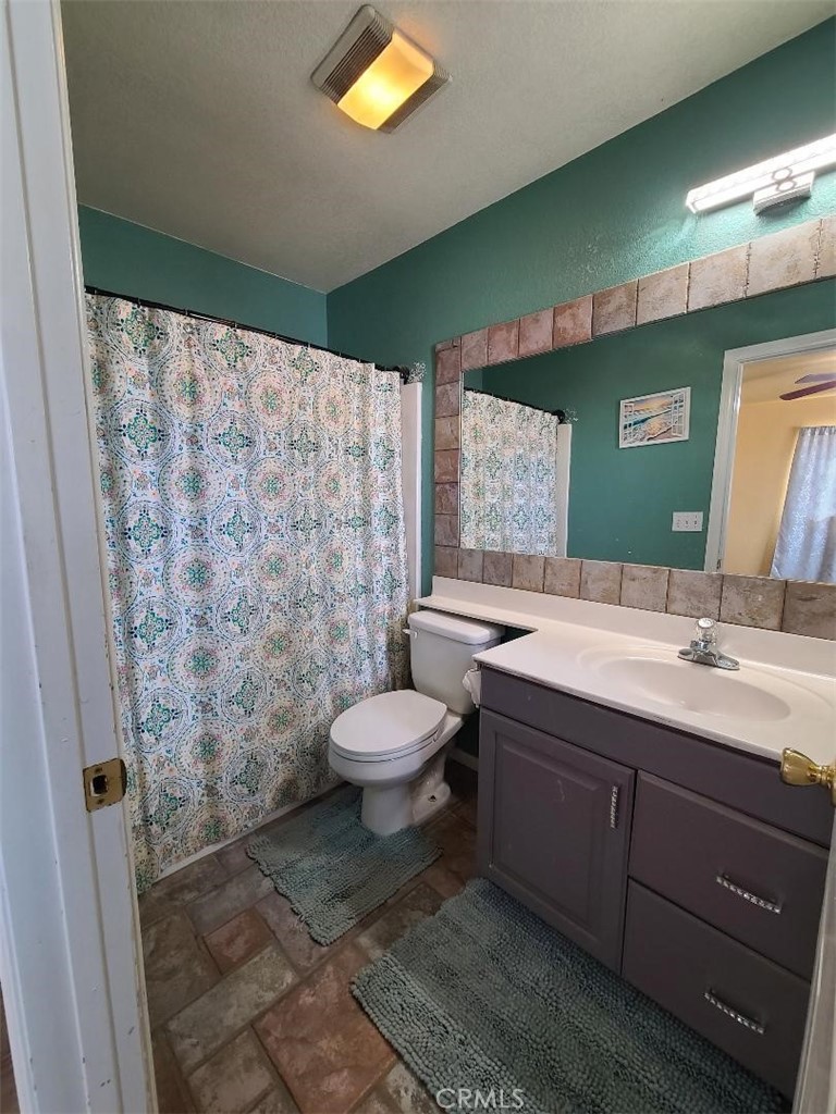 8725 Monte Vista Road Phelan, CA 92371 - Photo 17 of 31 a spacious bathroom with a granite countertop sink a toilet and a mirror