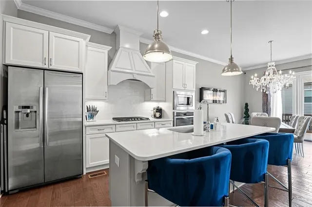 a kitchen with granite countertop a sink a center island stainless steel appliances and cabinets