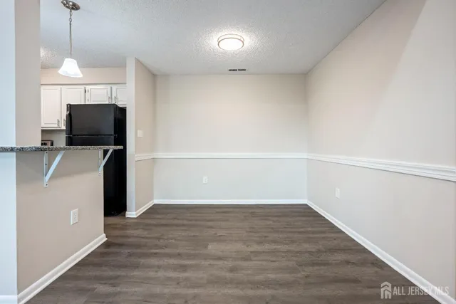 a view of a kitchen with refrigerator and wooden floor