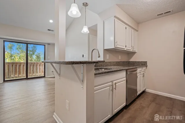 a kitchen with granite countertop white cabinets and a wooden floor