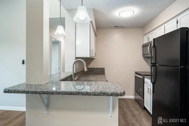 a kitchen with stainless steel appliances granite countertop a sink a refrigerator and a granite counter tops