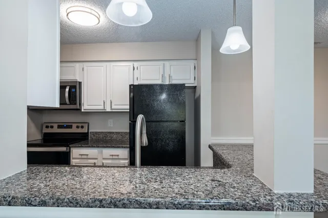 a kitchen with stainless steel appliances granite countertop a refrigerator a stove and a sink