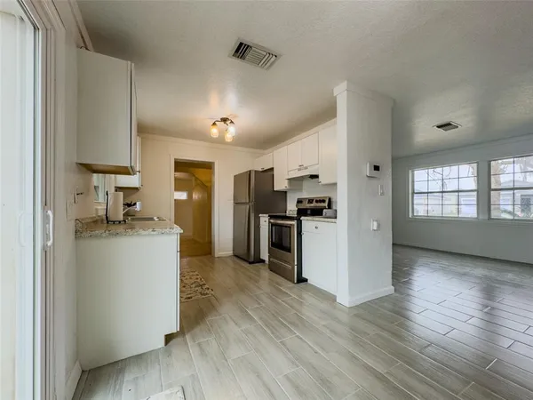 a kitchen with granite countertop a sink cabinets stainless steel appliances and a window