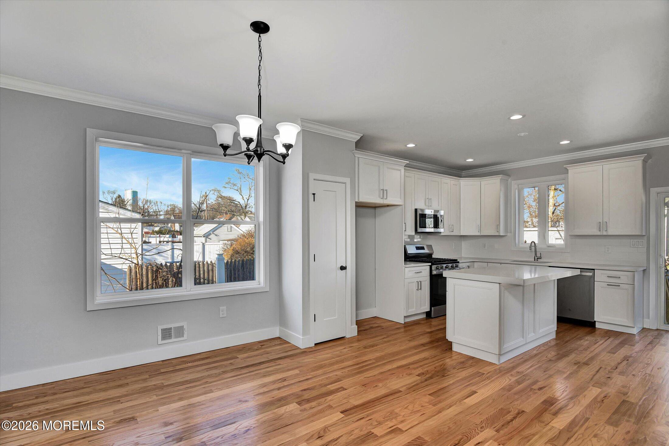910 Malden Drive Keyport, NJ 07735 - Photo 11 of 38 a kitchen with stainless steel appliances granite countertop a refrigerator a stove a sink dishwasher and a dining table with wooden floor