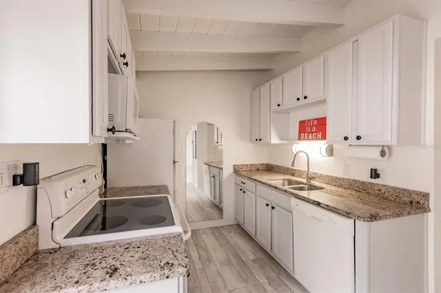 a kitchen with granite countertop a sink stove and refrigerator