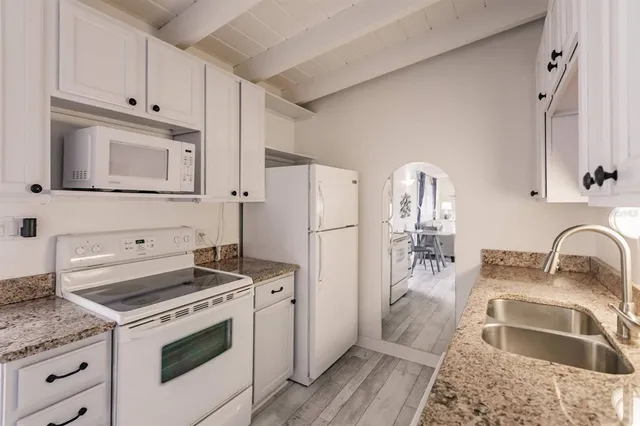 a kitchen with granite countertop a sink stove and refrigerator