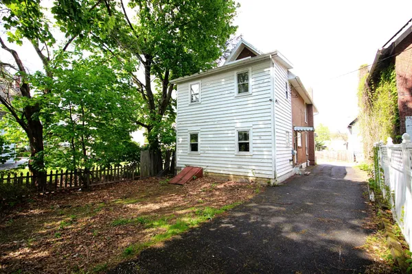 a view of a house with a small yard and large tree