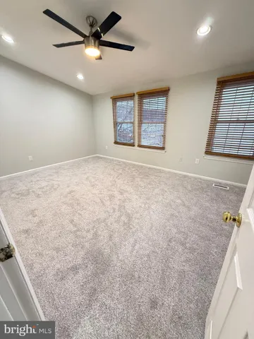 an empty room with windows and ceiling fan