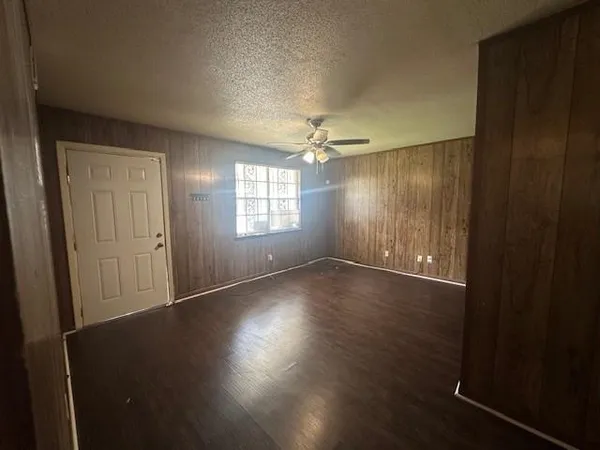 an empty room with wooden floor cabinet and windows