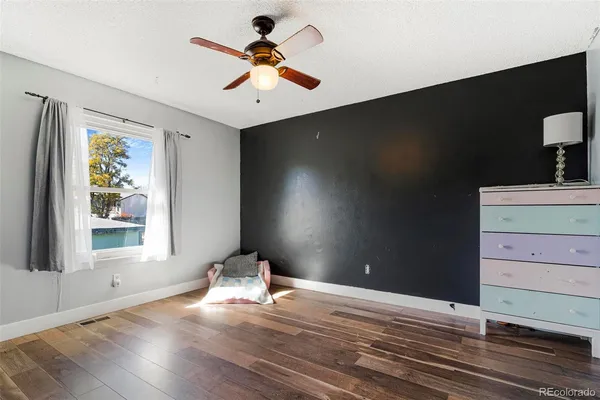 a view of empty room with wooden floor and fan