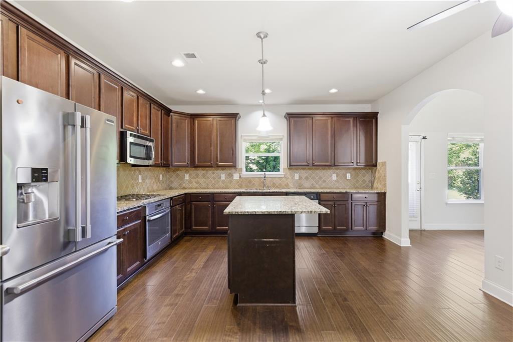 2573 Madison Mae Lane Grayson, GA 30017 - Photo 20 of 51 a kitchen with kitchen island granite countertop wooden floors stainless steel appliances a sink and a window