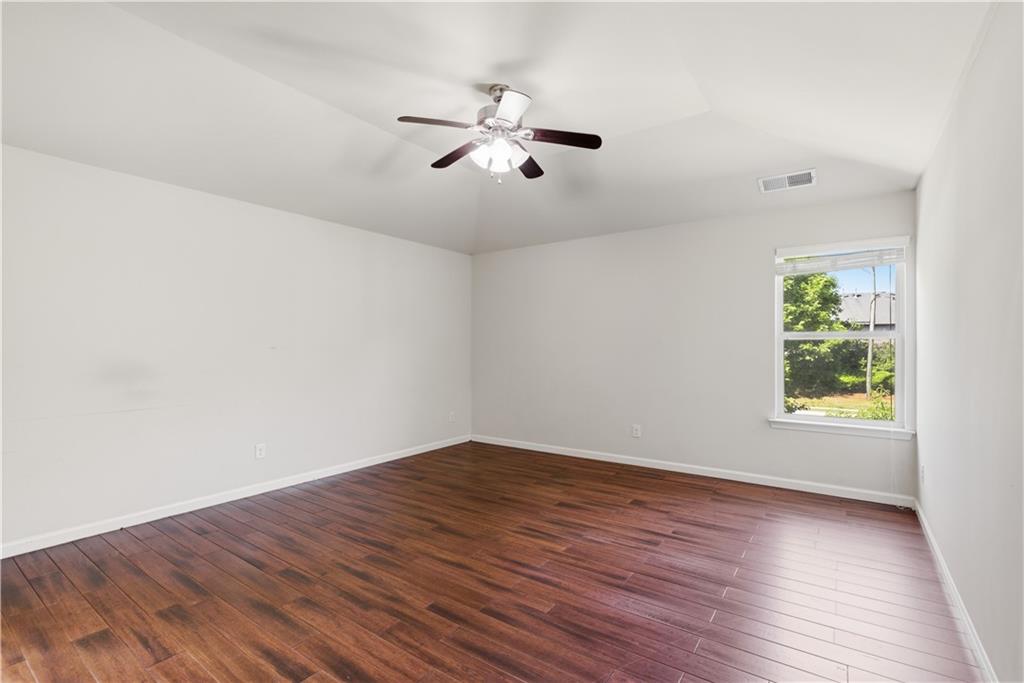 2573 Madison Mae Lane Grayson, GA 30017 - Photo 37 of 51 an empty room with wooden floor chandelier fan and windows