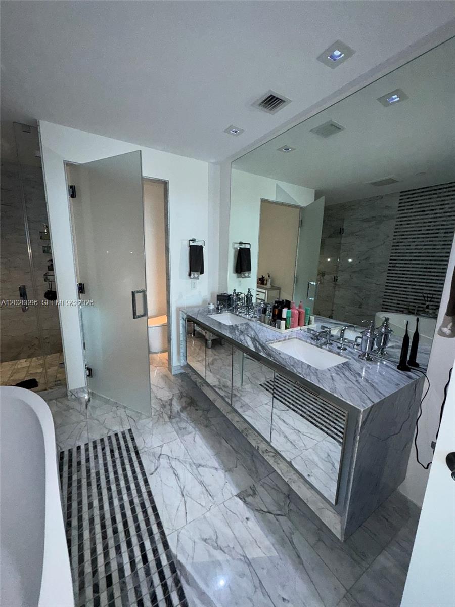 788 Northeast 23rd Street, Unit 1202 Miami, FL 33137 - Photo 22 of 64 a spacious bathroom with a granite countertop sink a mirror and a shower