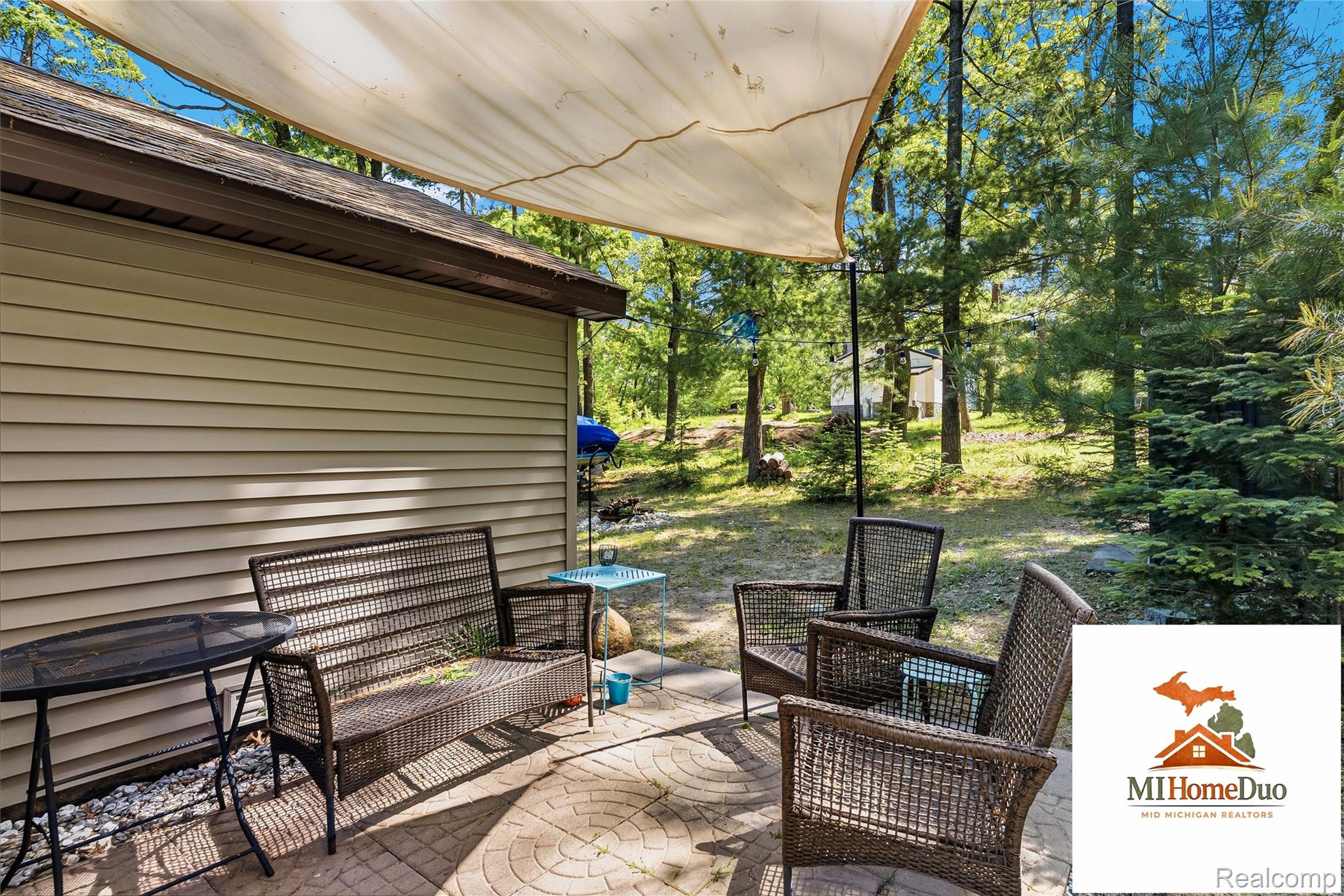 6960 Rumsay Street Harrison, MI 48625 - Photo 15 of 29 Paved patio area featuring a sun shade and surrounded by mature trees