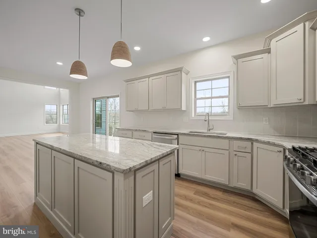 a kitchen with stainless steel appliances granite countertop a sink a stove and a wooden floors