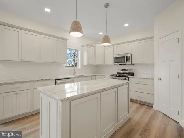 a kitchen with kitchen island granite countertop white cabinets white stainless steel appliances with a sink and dishwasher