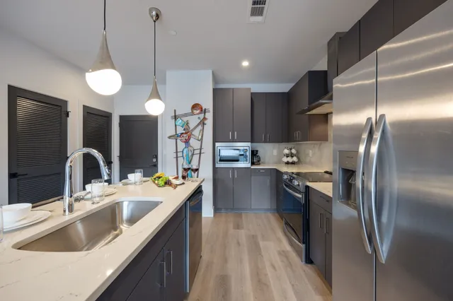 a kitchen with stainless steel appliances granite countertop a sink a stove and a refrigerator