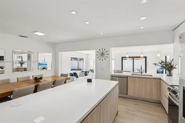 a large white kitchen with a sink large window and cabinets