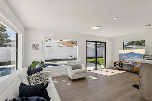 a living room with furniture floor to ceiling window and a flat screen tv