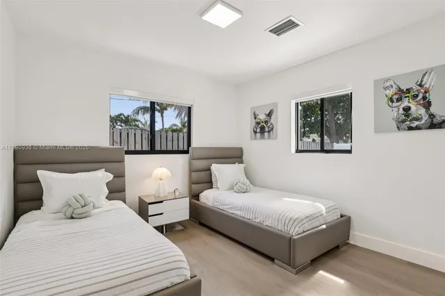 a bedroom with two beds and a painting on the wall
